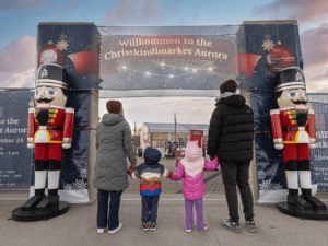 A family in front of the entrance to the Christkindlmarket Aurora