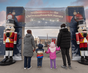 A family in front of the entrance to the Christkindlmarket Aurora